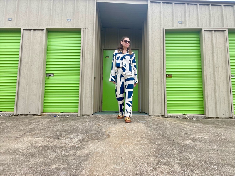 a woman in a blue and white pattern linen long sleeve and pant set  in front for green neon doors