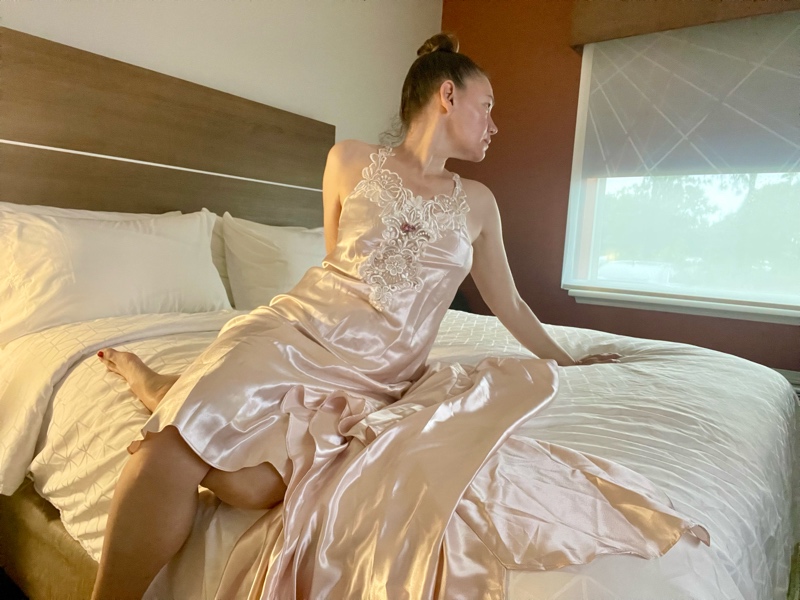 a woman in a pink peignoir set on a white bed