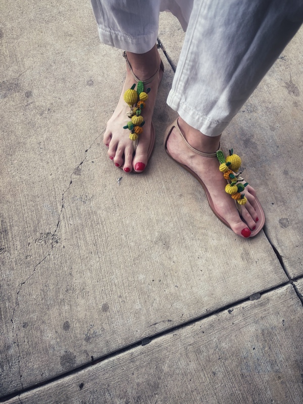 close up of rafia sandals with citrus and bees